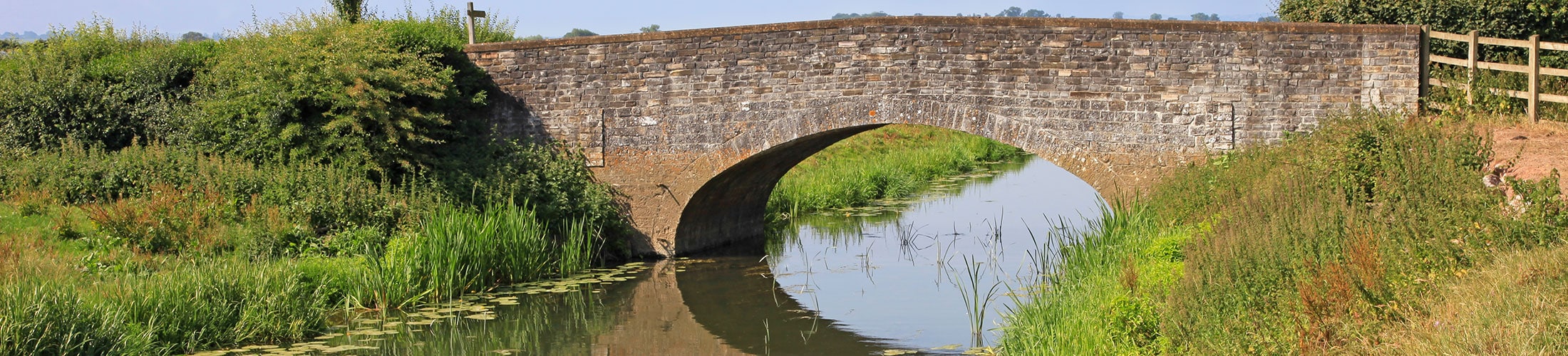 An old stone bridge spans a country river in England
