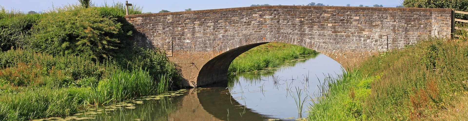 An old stone bridge spans a country river in England